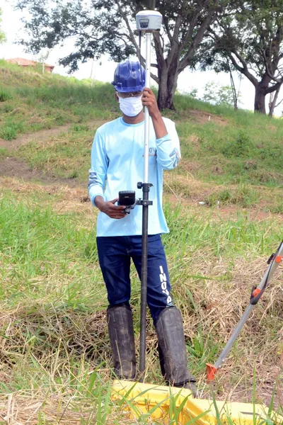 Profissional da equipe de campo com receptor GNSS em área de mato